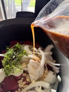 braising liquid for steak bites being poured into a slow cooker