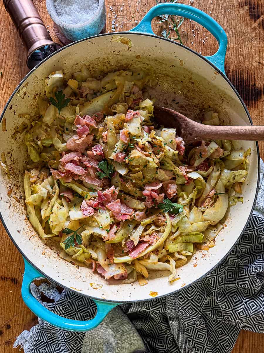 sautéed cabbage in a large braiser on top of a wooden surface