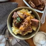 slow cooker steak bites served over mashed potatoes in a bowl