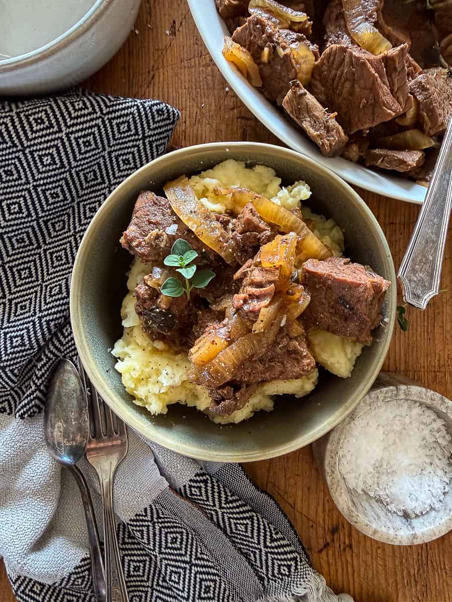 slow cooker steak bites served over mashed potatoes in a bowl